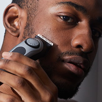 man using trimmer to shave beard