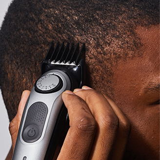 man using trimmer to trim on side of head